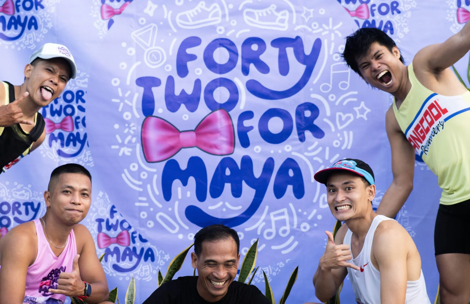 A joyful group of runners posing in front of the purple race backdrop